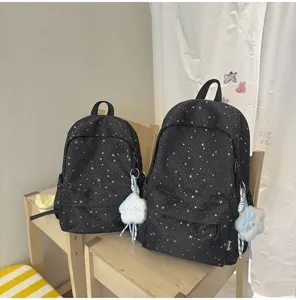 Details des schwarzen Rucksacks mit Sternenmuster, kompakte Struktur und süßer Plüschanhänger.