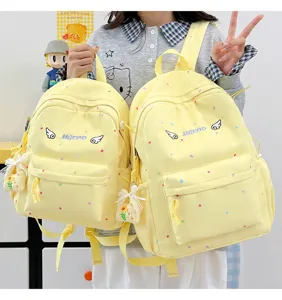 Detailansicht des gelben Polka-Dot-Schulrucksacks mit Flügelstickerei und seitlichen Anhängern.