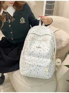Gros plan du joli sac à dos d'école étoilé avec un porte-clés duveteux en forme d'yeux.