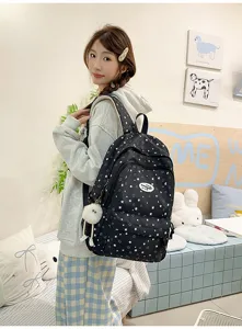 Vue détaillée du sac à dos scolaire noir à motif d'étoiles avec pendentif en peluche et compartiments.