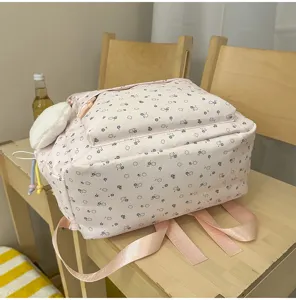 Detailansicht eines süßen rosa Blumen-Rucksacks mit Schulterriemen und Plüsch-Anhänger.