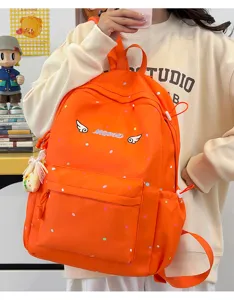 Detailansicht des orangefarbenen Polka-Dot-Schulranzens mit schicker Flügel-Stickerei.