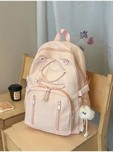 Pink corded school backpack detail showing front zipper pocket and cute plush charm.