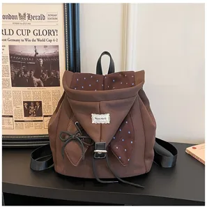 Detailansicht des braunen Kapuzen-Rucksacks mit blauen Punkten, süßer Schleife und Kordelzug.