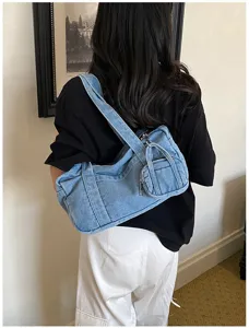 Denim shoulder bag detail view showcasing vintage washed texture and attached mini coin pouch.