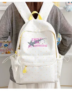 Detail view of white polka dot canvas school backpack featuring rocket star print and pockets.