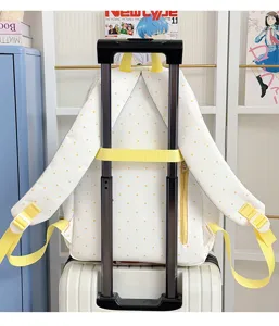 Detail view of cute white and yellow polka dot student backpack mounted on luggage handle.