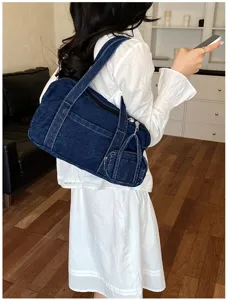 Detail view of the casual dark blue denim shoulder bag worn on shoulder with mini pouch.