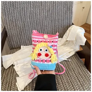 Detailansicht der süßen Häkel-Handytasche mit handgemachten Strickstreifen und Puppengesicht.