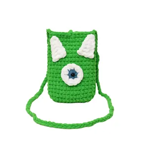 Handmade crochet phone bag detail, cute green monster design with single eye, cross-body strap.