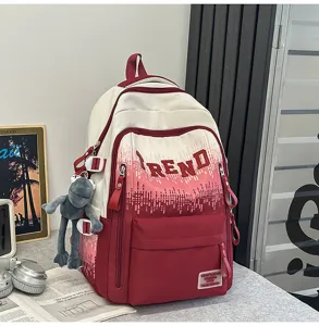 Detail view of the red and white gradient student backpack, showing front pocket and cute frog pendant.