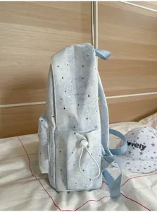 Detailansicht eines niedlichen hellblauen Rucksacks mit Sternenmuster und Seitentasche.