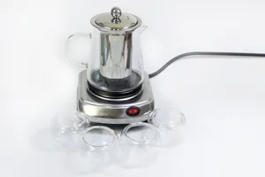 Mini set di stufa riscaldante elettrica con teiera in vetro e quattro tazze per tè.