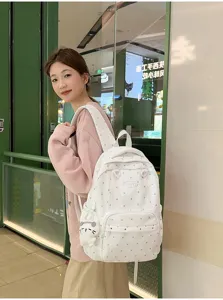 Gros plan détaillé du joli sac à dos d'école à pois avec pendentif porté par le modèle.
