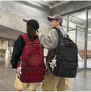 Detail view of stylish camouflage backpack with multiple compartments and cute bear pendant.