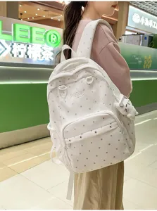 Vue détaillée du joli sac à dos d'école à pois, avec poche avant et pendentif charmant.