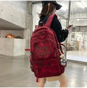 Close-up detail of the red camo fashion backpack with multi-compartments and cute bear pendant.