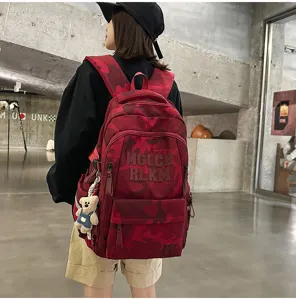 Detail shot of a stylish red camo backpack with multi-compartments and bear pendant.