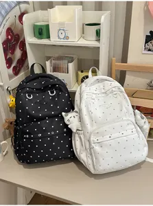 Vue détaillée de sacs à dos décontractés à pois noirs et blancs avec de charmants pendentifs.