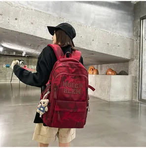 Detailed view of the red camo backpack showcasing multi-compartment design and cute bear pendant.