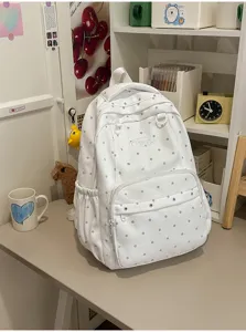 Vue détaillée du sac à dos blanc à pois sur un bureau bien rangé pour l'école quotidienne.