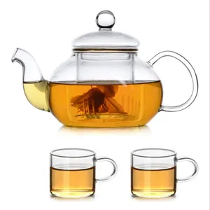 Clear heat-resistant glass teapot and two cups set for loose leaf tea and blooming flowers.