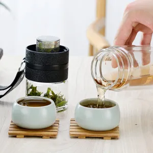 Gourde infuseur à thé en verre à double paroi avec tasses et sous-verres en bois pour le bureau.