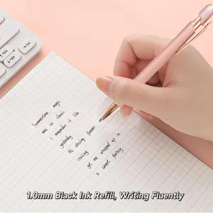 Close-up detail of a pink retractable ballpoint pen writing smoothly on grid paper.