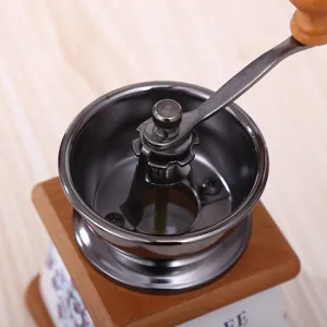 Nahaufnahme der manuellen Vintage Kaffeemühle mit Holzsockel und Metallkurbel.
