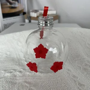Comederos para colibríes de vidrio transparente en forma de bombilla con flores rojas.