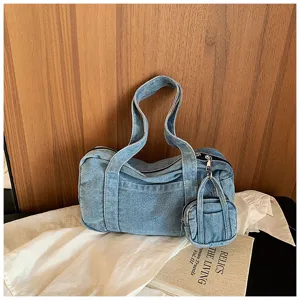 Detailed shot of vintage washed denim shoulder bag with mini pouch on wooden and cloth background.
