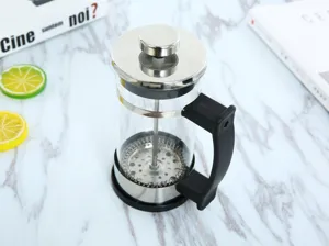 Detailweergave van glazen french press koffiebereider met roestvrijstalen filter en greep.