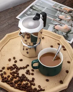 Aluminium Espresso Moka Kocher mit gruener Keramiktasse und Kaffeebohnen Detail