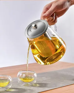 Dettaglio della teiera in vetro trasparente con filtro mentre versa il tè fresco.