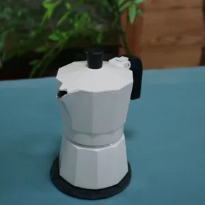 Close-up detail of the white double-valve moka pot espresso maker on a tabletop.