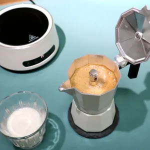 Detail shot of a stovetop moka pot brewing espresso with rich crema on a kitchen counter.