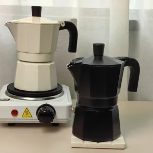 Detailed view of dual-valve moka pots in black and white styles, placed on a hot plate.
