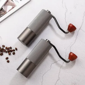 Macinino da caffè manuale con nucleo in acciaio inossidabile e manovella grigio elegante.