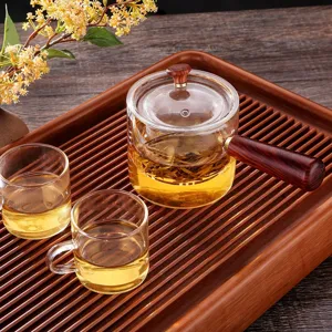 Clear glass teapot with wooden handle and cups set for brewing health tea, modern.