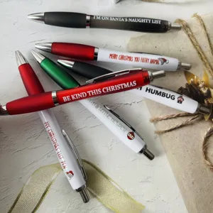 Close-up detail of colorful Christmas ballpoint pens set with funny holiday quote prints.