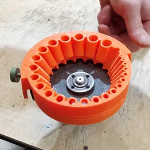 Detail view of multifunctional drill bit sharpener component, orange plastic shell and metal gear.
