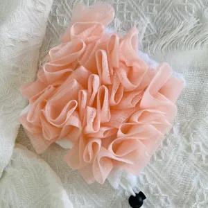 Close-up detail van de roze netjesspons en witte handdoek, zacht badkameraccessoire textuur.