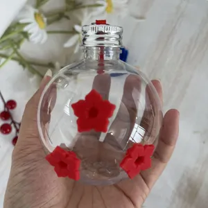 Comedero de colibrí de plástico transparente con flores rojas vista de detalle manual.