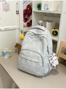 Vue détaillée du sac à dos gris à pois avec poche zippée et adorable pendentif chaton.