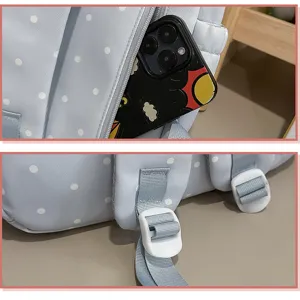 Vue detaillee du sac a dos bleu clair a pois montrant la poche avant et les boucles blanches.