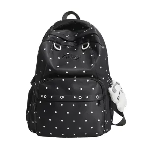 Vue détaillée du sac à dos à pois noir et blanc montrant la poche avant et le logo.