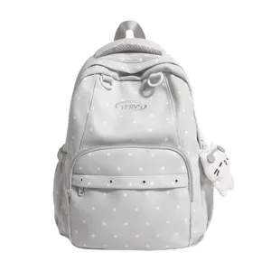 Vue détaillée du sac à dos gris à pois avec poche avant et joli pendentif en peluche.