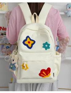 Detail van nylon rugzak met kleurrijke getufte bloempatches en een schattige berenhanger.