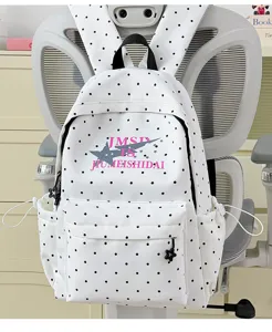 Detailed view of white polka dot backpack with star print, front pocket and zipper charms.