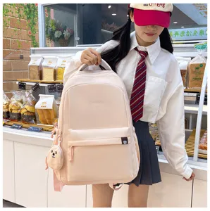 Vista dettagliata dello zaino scolastico in nylon rosa con ciondolo a orsetto e tasca frontale.